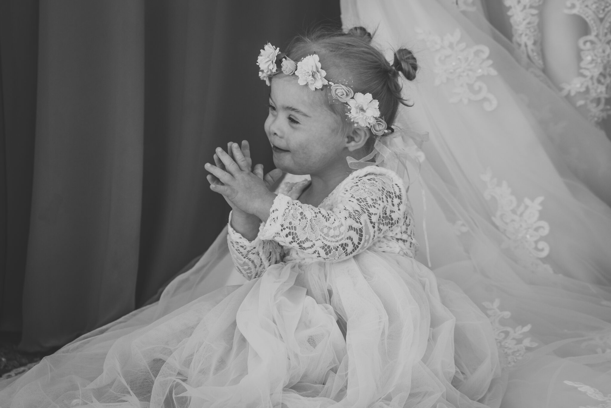 Black and white photo of a small child in a flower crown and dress