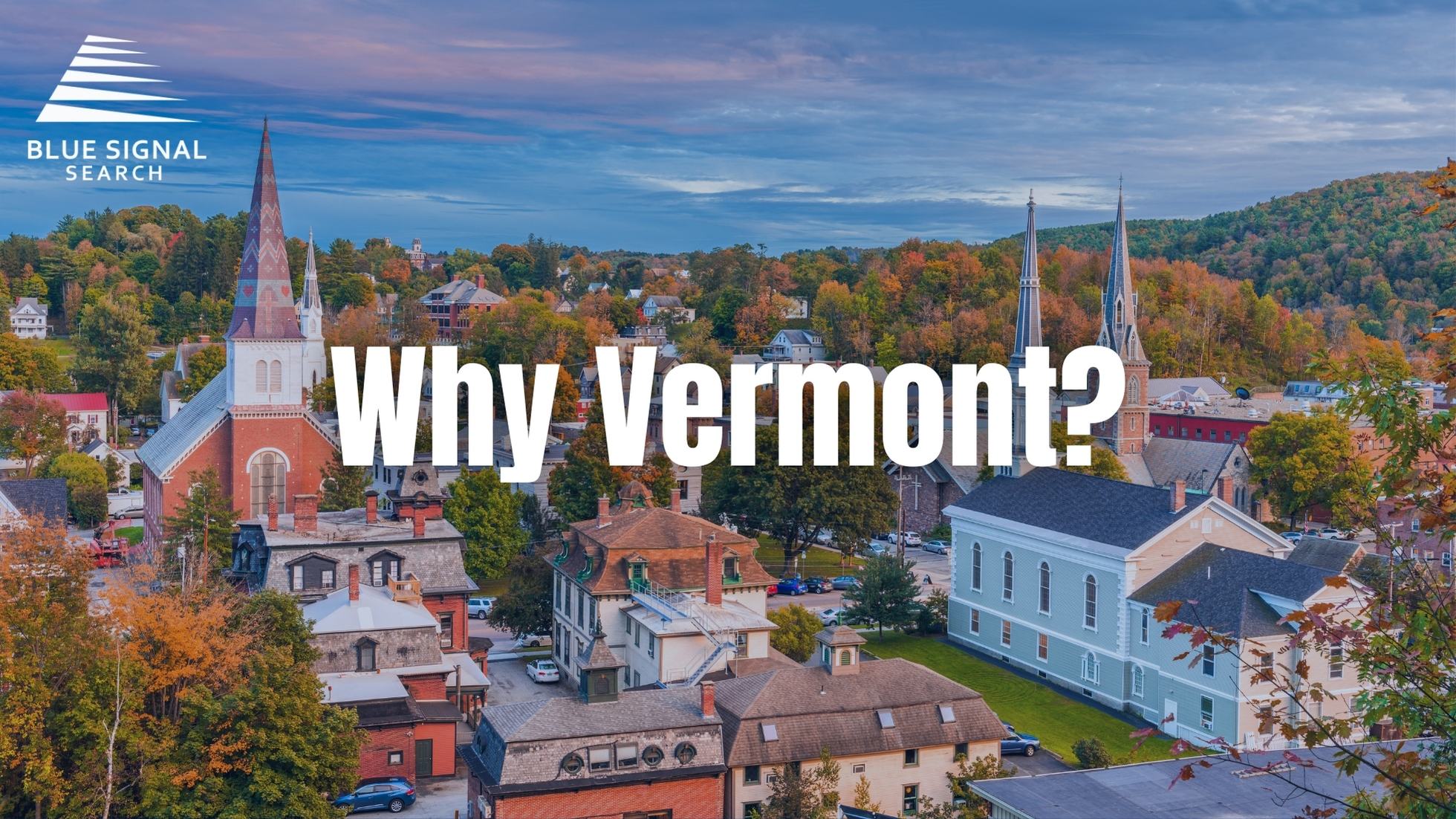 Scenic view of Vermont's landscape with colorful autumn trees, historic buildings, and church steeples under a soft blue sky.