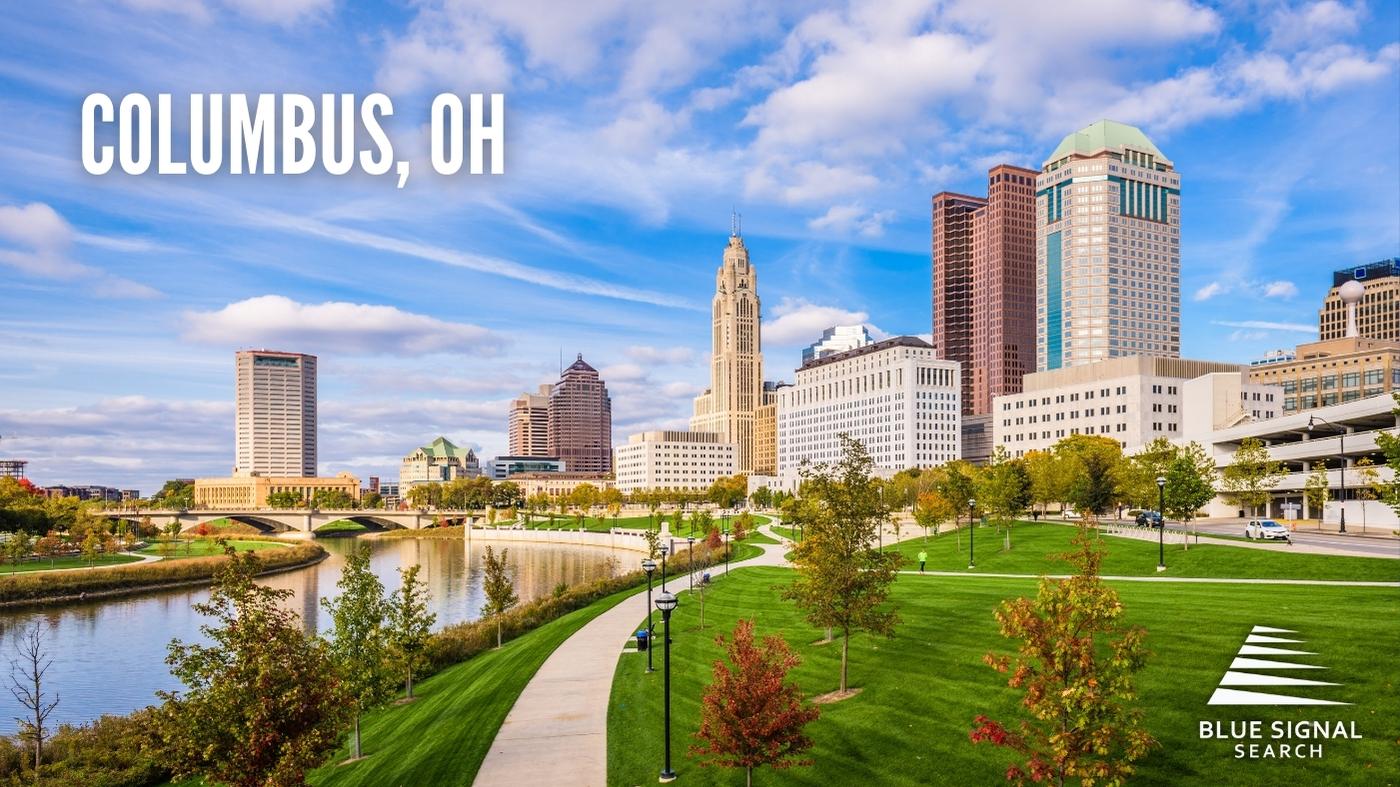 Aerial view of downtown Columbus, OH, with a river and green parkland in the foreground.