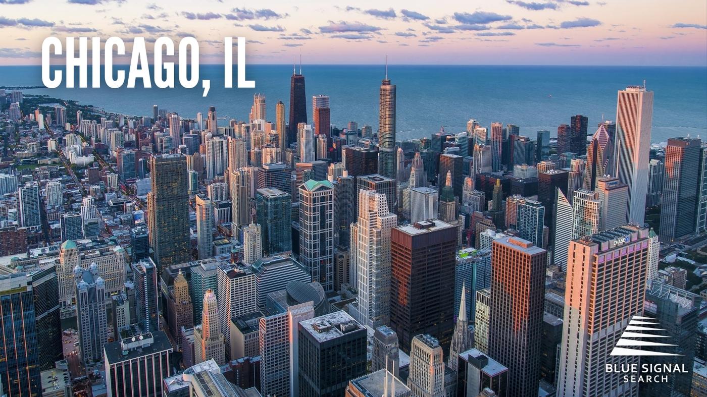 Aerial view of downtown Chicago, IL, with high-rise buildings and Lake Michigan in the background.