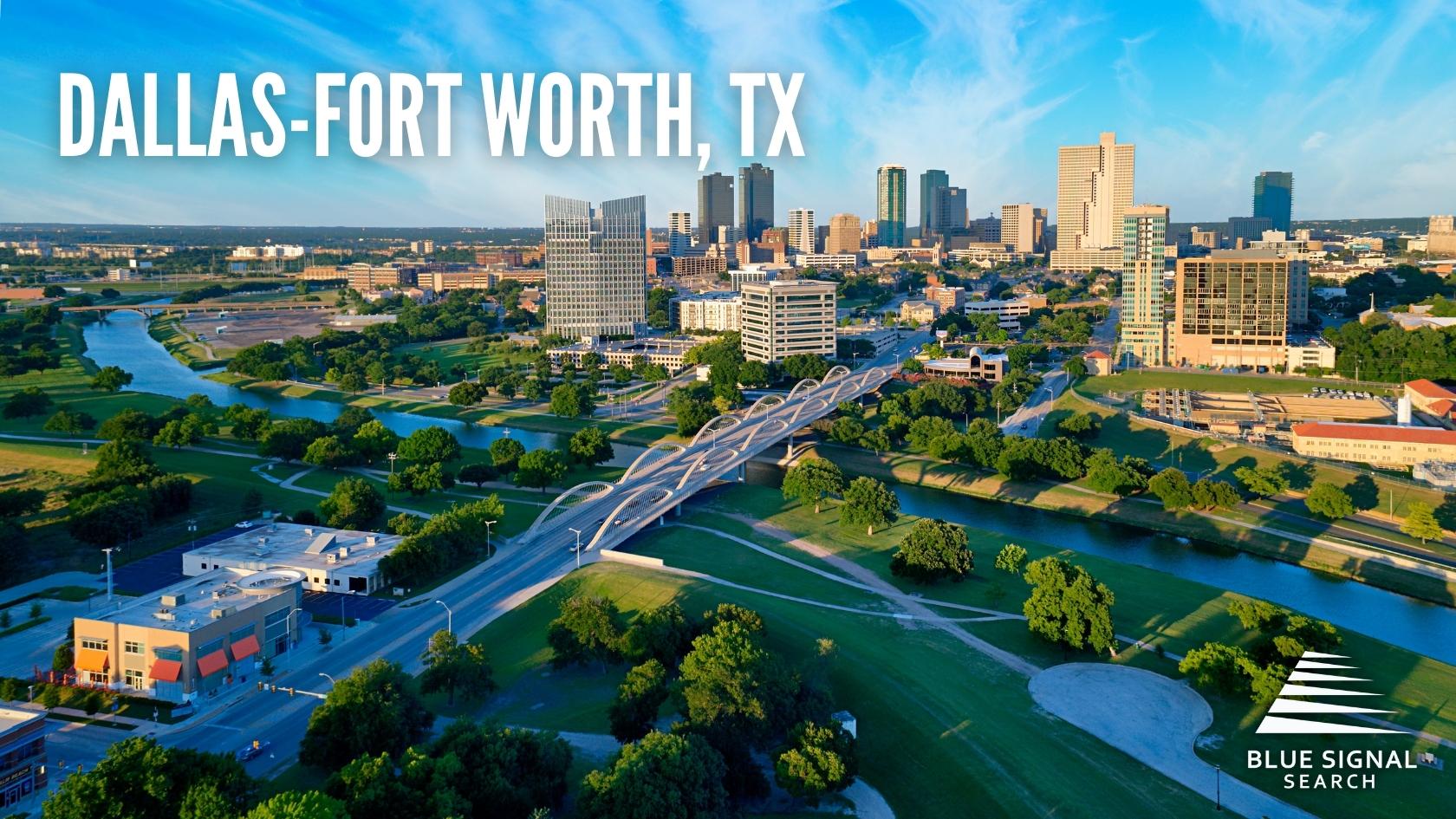 Aerial view of Dallas-Fort Worth, TX, with a river and a bridge in the foreground and downtown buildings in the background.