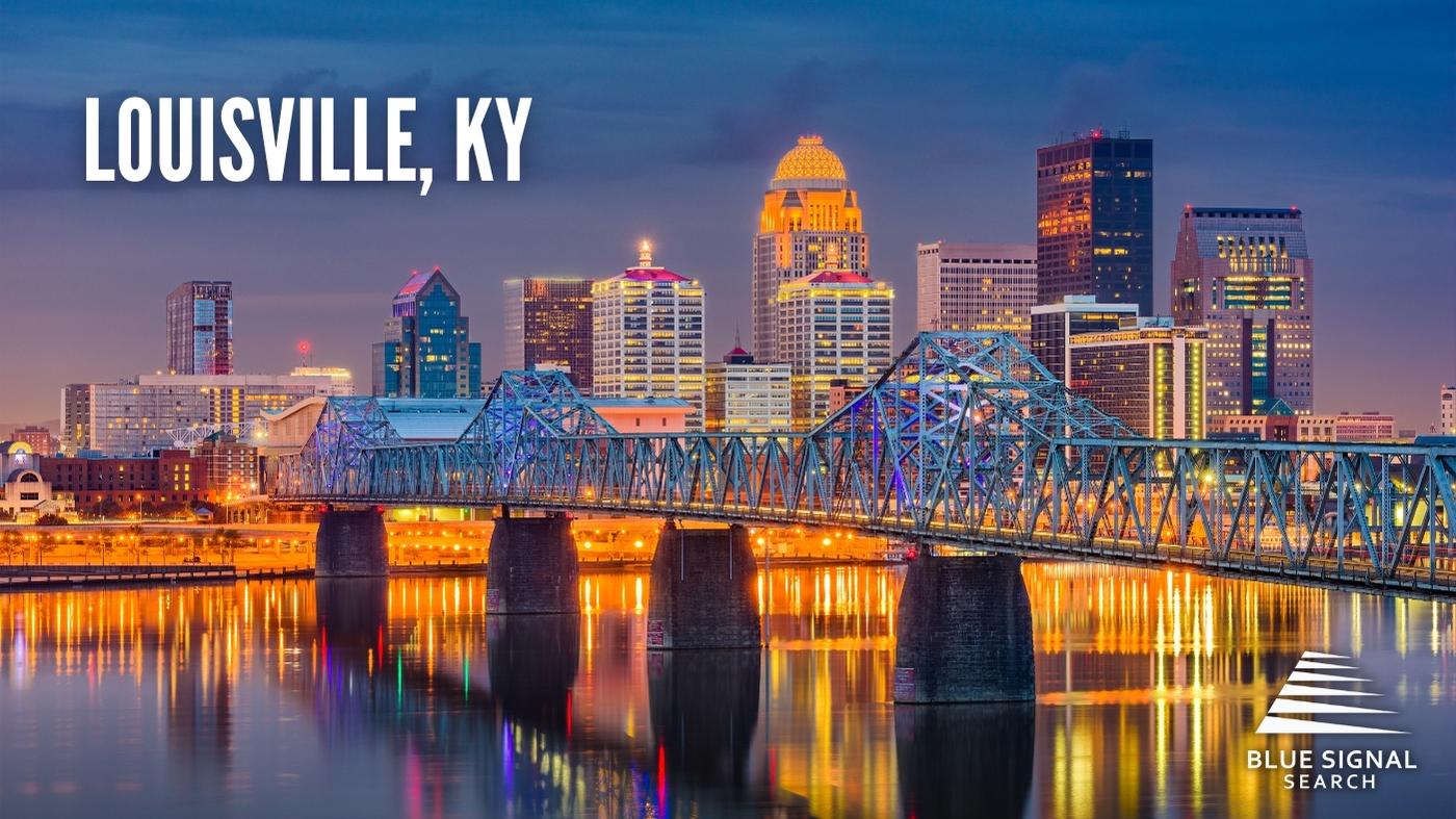 A brightly lit downtown Louisville, KY, at night, with a prominent bridge crossing a river.