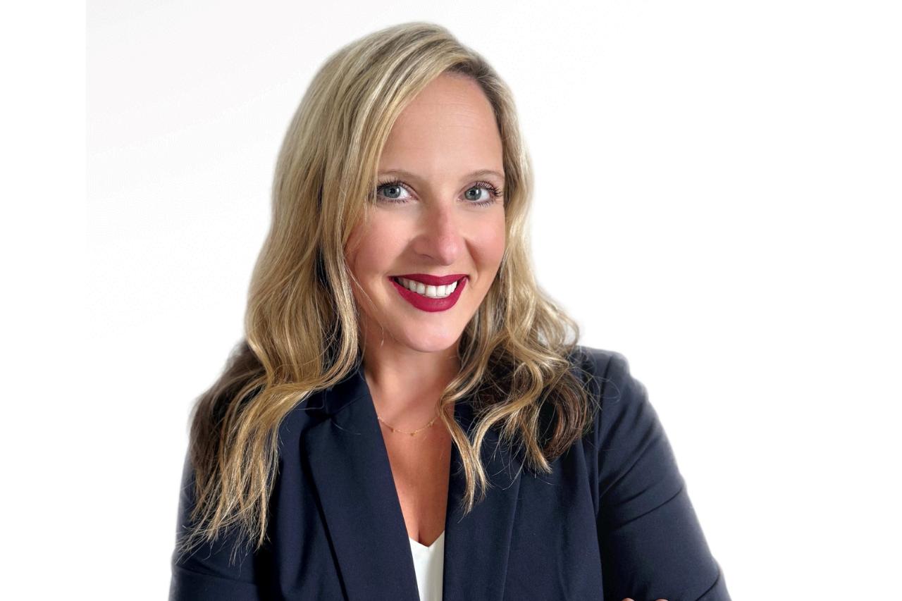 Professional head shot of recruiter Courtney Bernard with Blue Signal Search. She is wearing a navy blazer, white shirt, and is against a white background smiling.