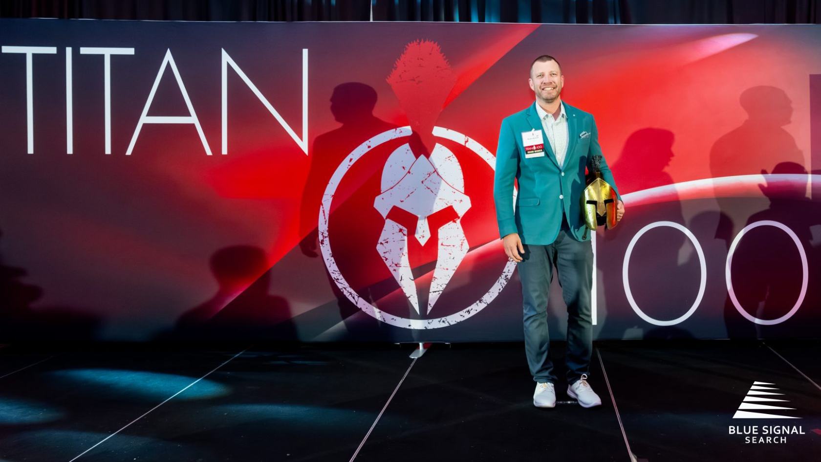 Blue Signal CEO Matt Walsh holding his Titan knight helmet at the 2024 Phoenix Titan 100 ceremony.