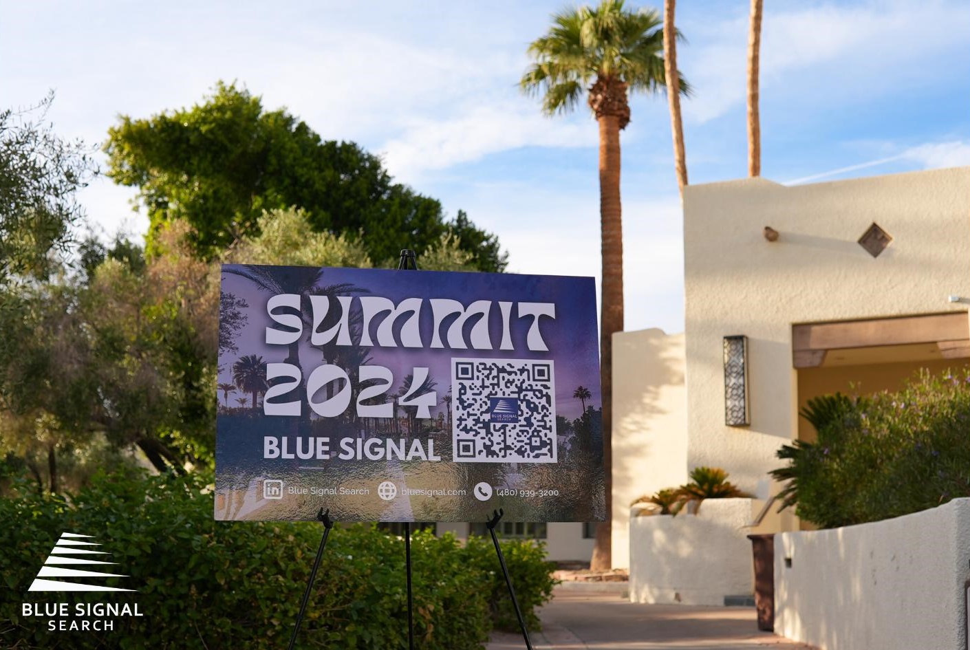 Sign at Blue Signal Summit 2024 with QR code, surrounded by palm trees at the Wigwam Resort.