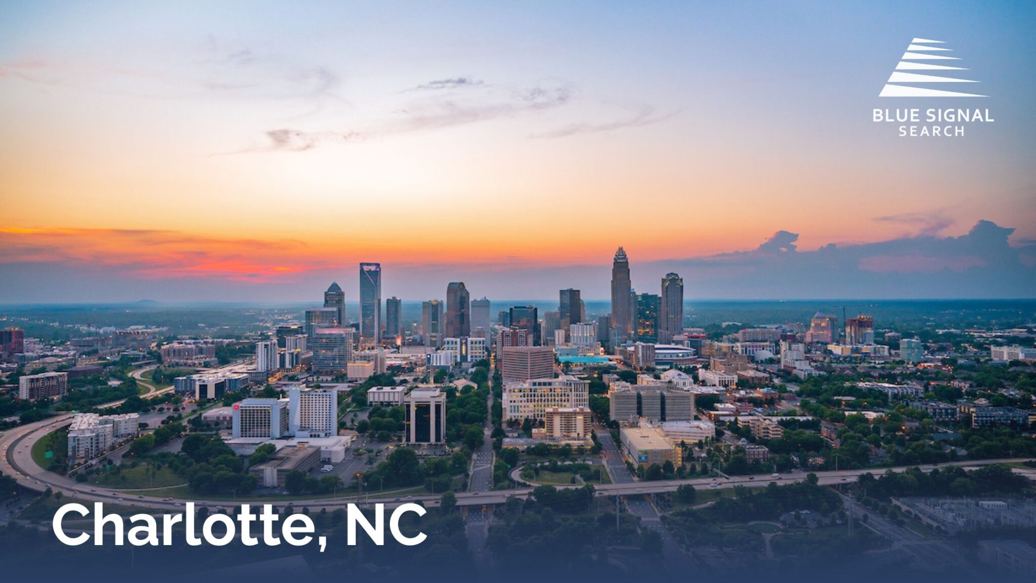 Charlotte skyline at sunset with modern skyscrapers and surrounding city landscape.