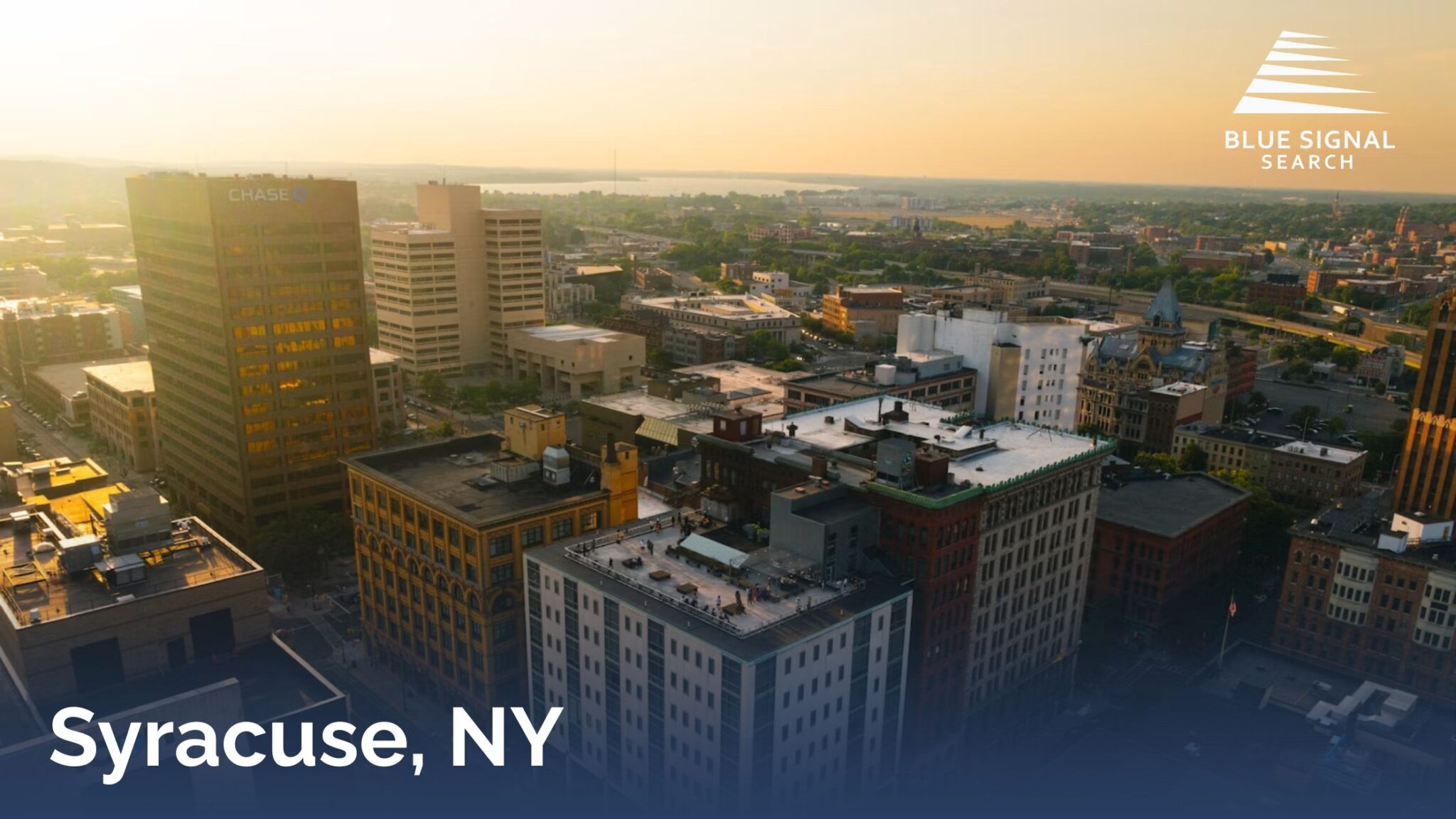 Downtown Syracuse skyline during sunset with office buildings and city streets.